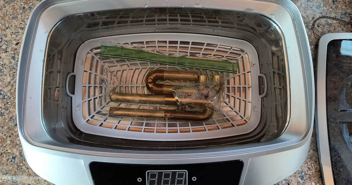 Ultrasonic cleaning tank with a basket of bent metal tubes, a step in copper UHV cleaning